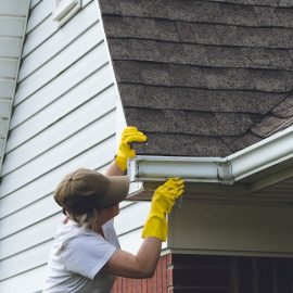 Woman Cleaning Gutters on Her House